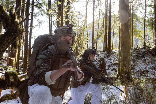 Army Man wearing Tactical Uniform and holding Machine gun in the Outdoor Rain Forest. Winter Warfare. Taken in British Columbia, Canada.