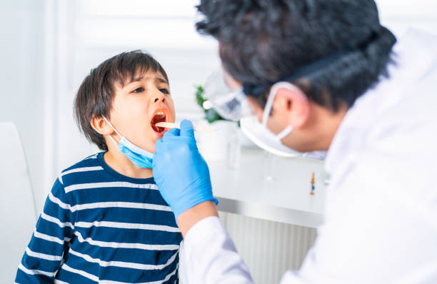 male pediatrician examining little child patient’s throat at clinic - doctor patient male tongue depressor imagens e fotografias de stock