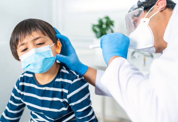 istock Male doctor examining boy's ear with a flashlight at clinic 1306247315