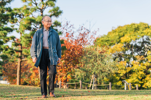 A senior adult man is enjoying taking a walk in nature.