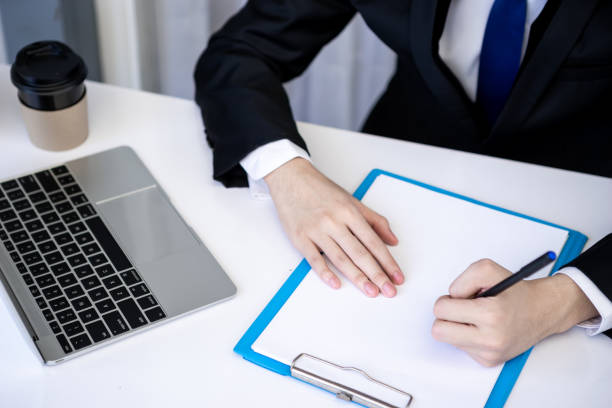 istock Asian business man dringking coffee wearing suit, enjoying watching educational webinar on laptop or laptop and smartphone. Smiling with chat and holding video call with clients partners. 1306248085