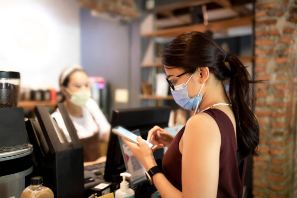 istock Young woman making contactless payment with smartphone at cafe 1306248903
