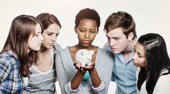 Student loan worries, perhaps? Young people peering at a piggybank.