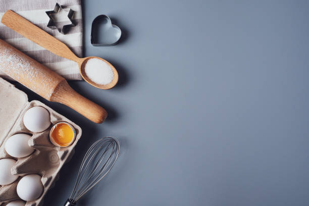 istock Different ingredients and kitchen utensils for making cookies or cupcakes, flat lay, copyspace. Eggs, rolling pin, whisk, flour, cookie molds, layout on a gray background. The concept of home baking 1306249955
