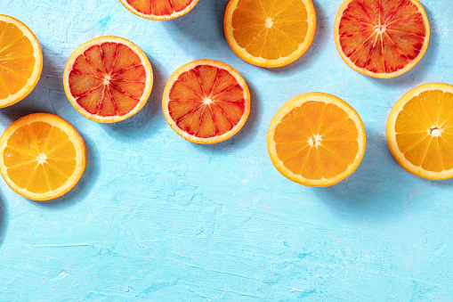 Summer background with fresh oranges on a blue background, overhead flat lay shot with copy space
