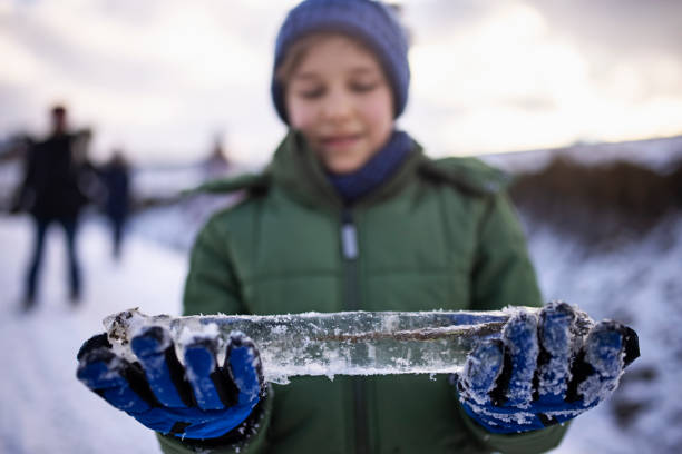 Kids enjoying hiking in hills on cold winter day. Kids are playing with icicles they have found on the side of the road. Little boy holding an icicle with a piece of plant frozen inside.Shot with Canon R5