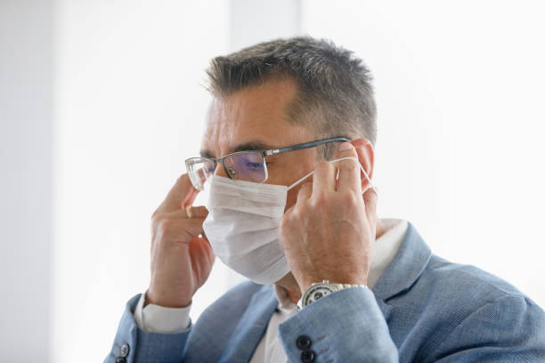 istock Businessman holding rubber bands and putting protective face mask on 1306254592