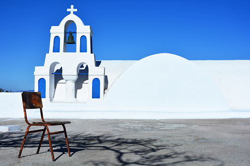 View of white and blue belfry with cross and bells of Greek orthodox church in Oia village, Santorini, Greece. Greek culture