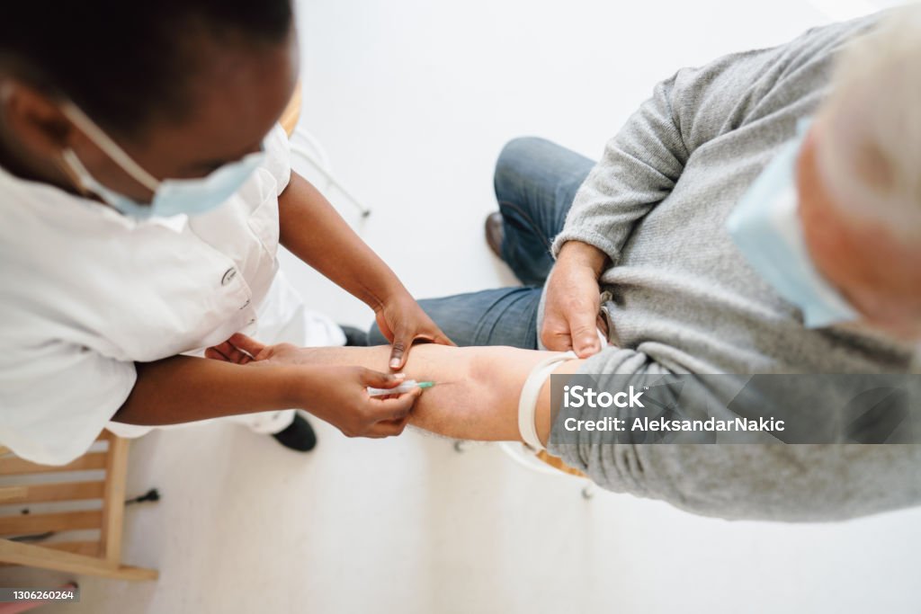 Nurse taking a blood sample from a patient Photo of a female nurse taking a blood sample from a patient with a needle Blood Test Stock Photo