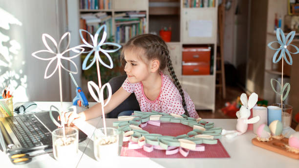 istock Girl doing wreath with toilet roll tube via online master class, zero waste Easter celebration 1306260341