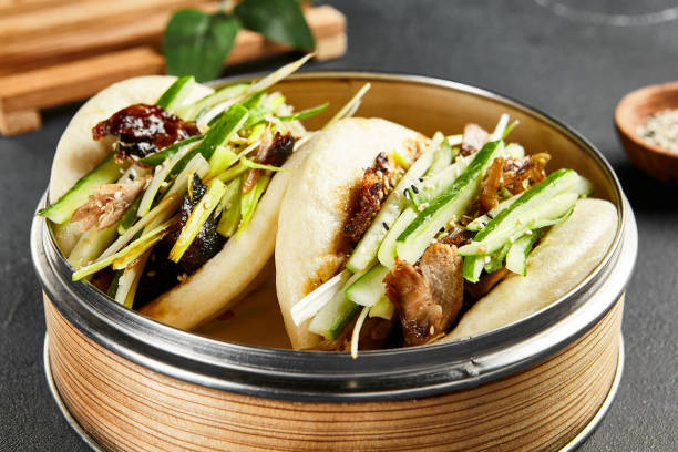 Bao bun with roast duck. Bamboo steamer on dark slate table. Chinese, asian, authentic food concept Bao bun with roast duck. Bamboo steamer on dark slate table. Chinese, asian, authentic food concept. hoisin sauce stock pictures, royalty-free photos & images