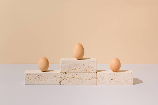 istock Three eggs standing on a travertine marble podium on a beige and gray background. 2021 Easter unique still life composition. Surreal retro creative scene. Minimal competition concept 1306264743