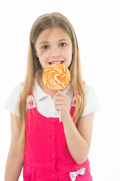Girl eat lollipop isolated on white. Little child enjoy candy on stick. Happy kid smile with swirl caramel. Candyshop concept. Childhood and happiness. Sweet mood. My favourite meal