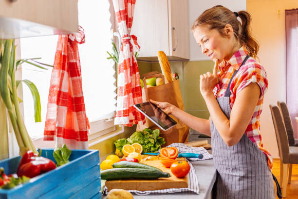 istock Young smiling woman cooking and using tablet. 1306265964