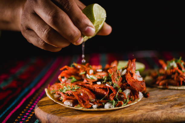 전통적인 다채로운 배경을 가진 멕시코 타코에서 압착되는 라임클로즈업 - mexican dish 뉴스 사진 이미지