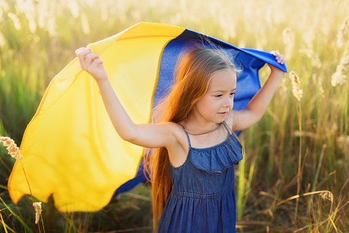 Girl blue and yellow flag of Ukraine in field. Ukraine's Independence Flag Day. Constitution day. 24 August. Patriotic holiday. Ukrainian kids. Celebrate national holiday.