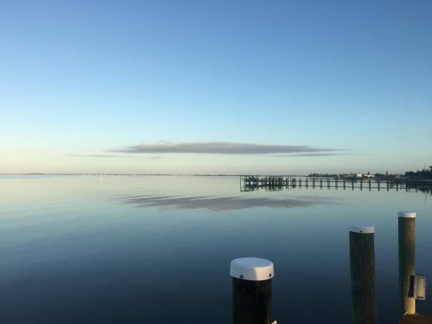 istock Calm dawn intracoastal waters with docks and reflected low patch of cloud 1306274629