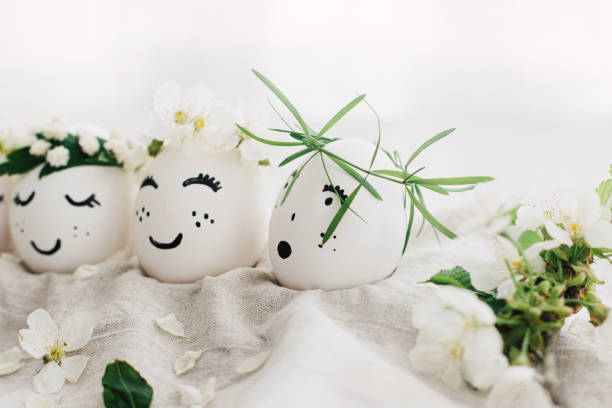 istock Easter eggs with drawn funny faces in floral wreaths on linen fabric with bloom. Happy Easter 1306274776