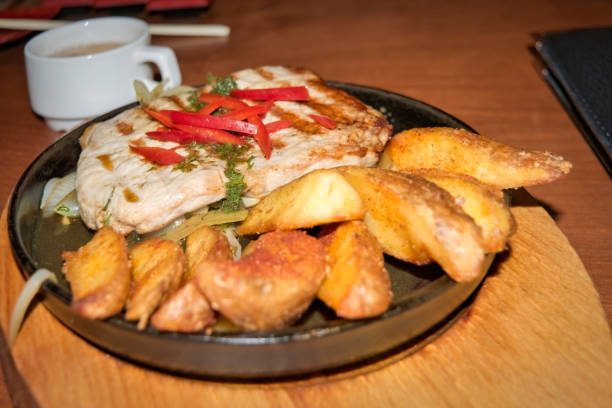 istock Pork steak with fried potatoes and onions on a cast-iron brazier. 1306275739