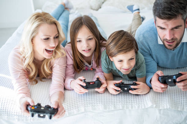 Playing Video Game At Home Family Playing With Video Games Console at Home family dependency mother family with two children stock pictures, royalty-free photos & images