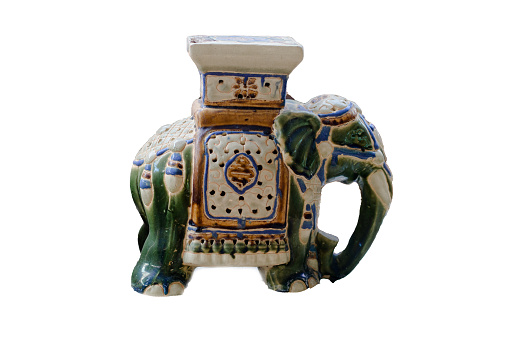 An old ceramic elephant statue on a white background