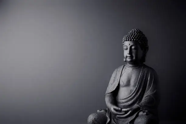 Photo of Meditating Buddha Statue on paper background. Copy space.
