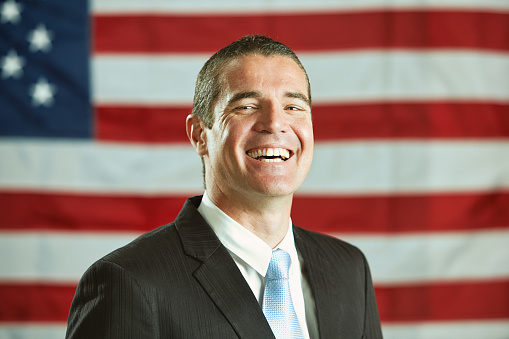 Happy man in a suit in front of the Stars and Stripes.