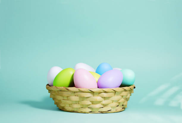 istock Easter background. A collection of Easter eggs in pastel colors in a basket on a blue-green background, with harsh shadows and light. 1306284684