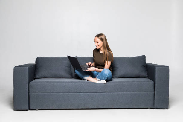 istock Woman lying on sofa at home working on laptop computer. Isolated on white background. 1306288100