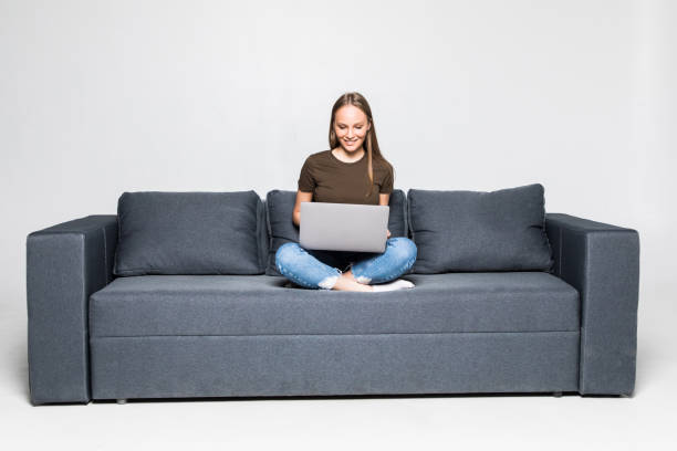 istock Woman lying on sofa at home working on laptop computer. Isolated on white background. 1306289821