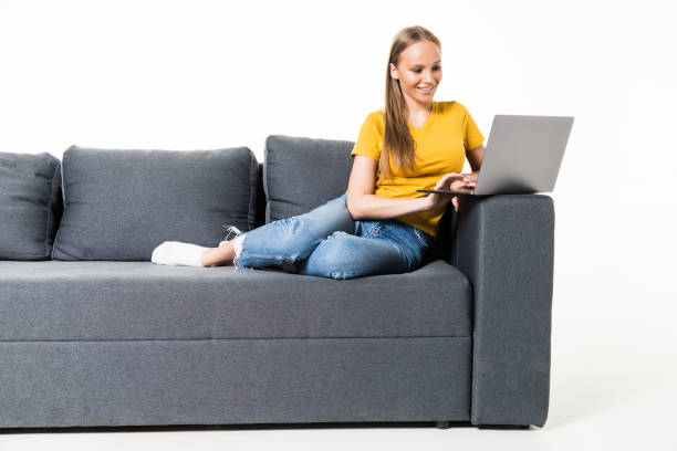 istock Woman lying on sofa at home working on laptop computer. Isolated on white background. 1306290470
