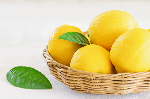 Group of whole organic lemon in wood basket on white background. Fresh lemon have high vitamin C and delicious sour taste for lemonade or cooking. Citrus or citron fruit concept.