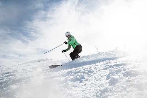Side view of woman splashing snow while skiing on a mountain