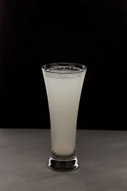 Photo of Milky white drink in clear glass. Alcoholic or non alcoholic drink on dark background with copy space