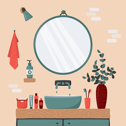 Cozy bathroom interior. Blue sink on wood counter with a large round mirror hanging above it. Vase with eucalyptus branches. Toothbrush, body care cosmetics, towel.