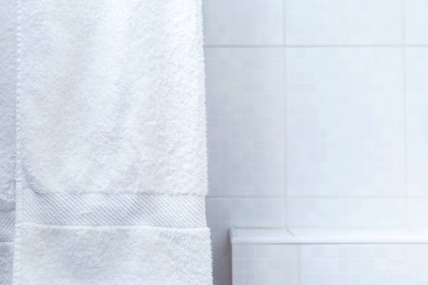 istock White towel hanging in the bathroom with space on white tile background 1306301478