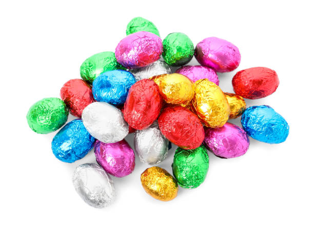 istock Many chocolate eggs wrapped in bright foil on white background, top view 1306301727