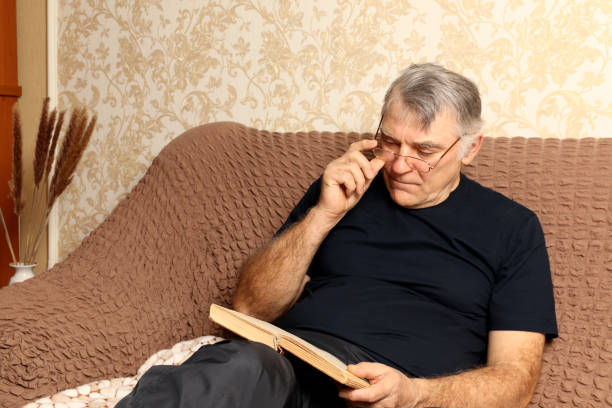 istock Time to rest. Concentrated man sitting on the couch reads an interesting book. 1306303584
