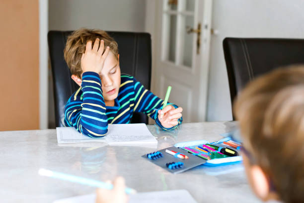 istock Two hard-working school kids boys making homework during quarantine time from corona and covin 19 pandemic disease. Children, brothers writing with pen, staying at home. Homeschooling concept. 1306303921