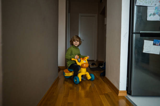 Cute young boy riding his tricycle in corridor