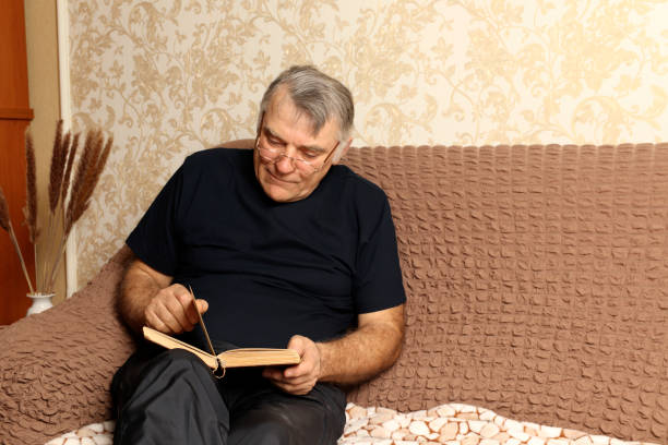 istock Time to rest. Concentrated man sitting on the couch reads an interesting book. 1306305426
