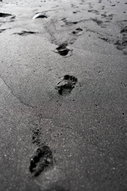 istock Footprints on the beach on black volcanic sand. 1306305610