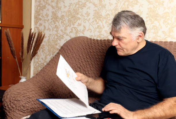 istock A man reading documents sitting on the couch in his living room. Remote work at home concept. Copy space 1306306077