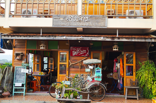 Old wooden house and coffee shop with trishaw outside in Chiang Kham in Chiang Rai province