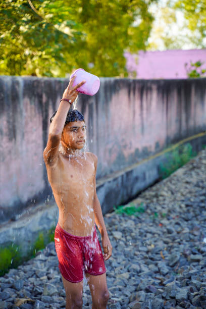 istock Cute indian poor child enjoy bathing in open place 1306307023