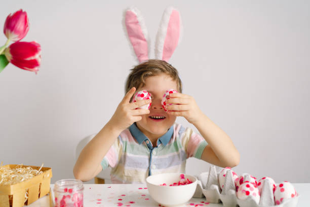istock A little boy in bunny ears decorates Easter eggs. 1306307480