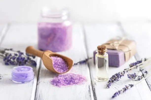 Lavender spa products on an old white wooden table. Body care products with lavender-oil, salt, cream, soap and dried lavender flowers. Selective focus
