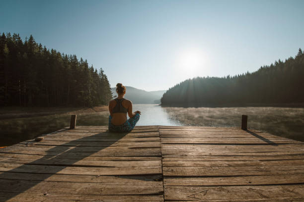 A rear view of a young woman wearing sports clothing, practicing yoga and enjoying a beautiful morning in the mountain.