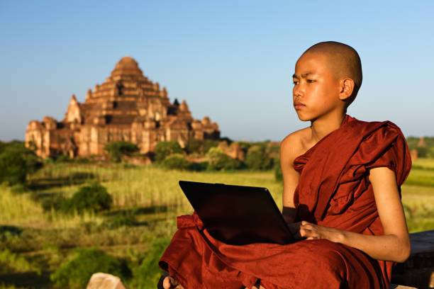 jeune moine bouddhiste utilisant l’ordinateur portatif - hinduism monk buddhism myanmar photos et images de collection