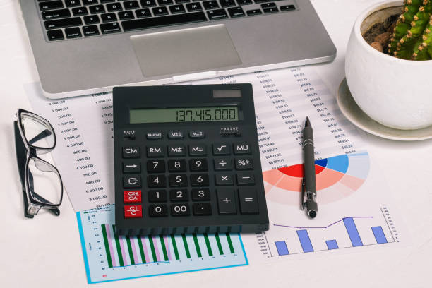 istock Calculator, laptop and financial documents on the desktop. Research and analytics in business. Enterprise development and banking. Accounting in the company 1306309420
